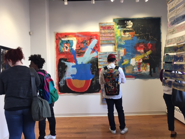 Four students examine artwork on the wall
